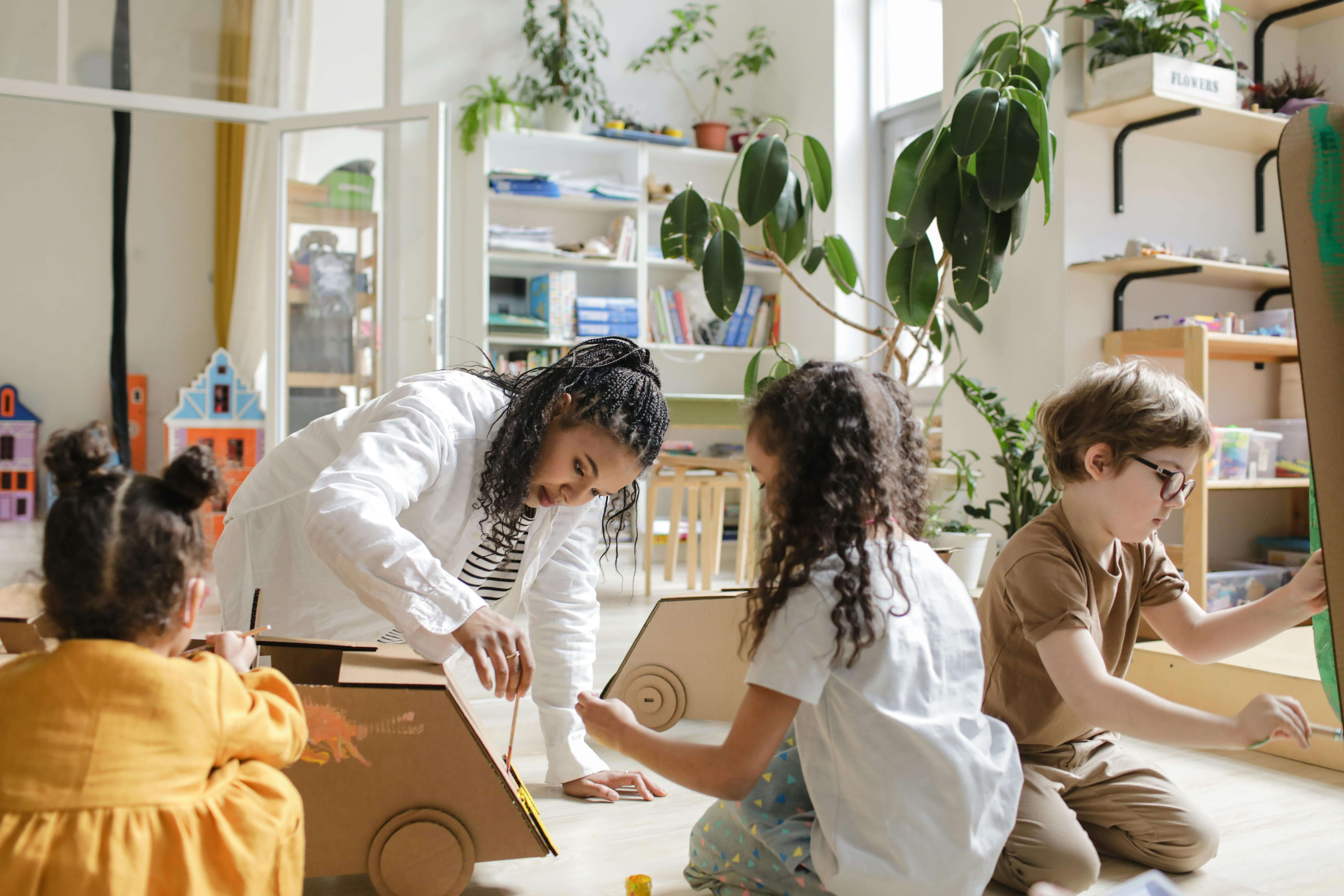 Adult and 3 kids painting cardboard car