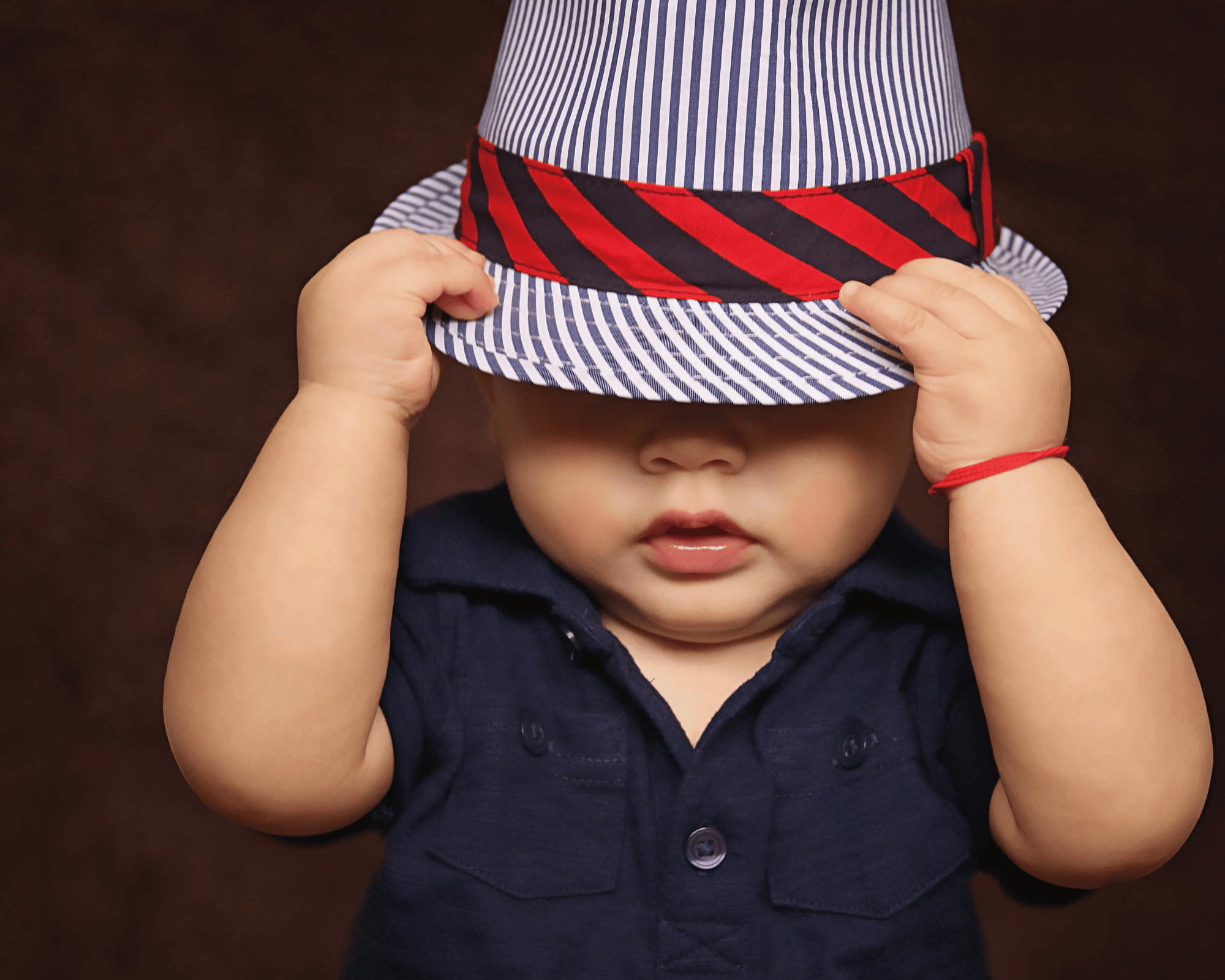 Baby boy wearing hat with red rim.