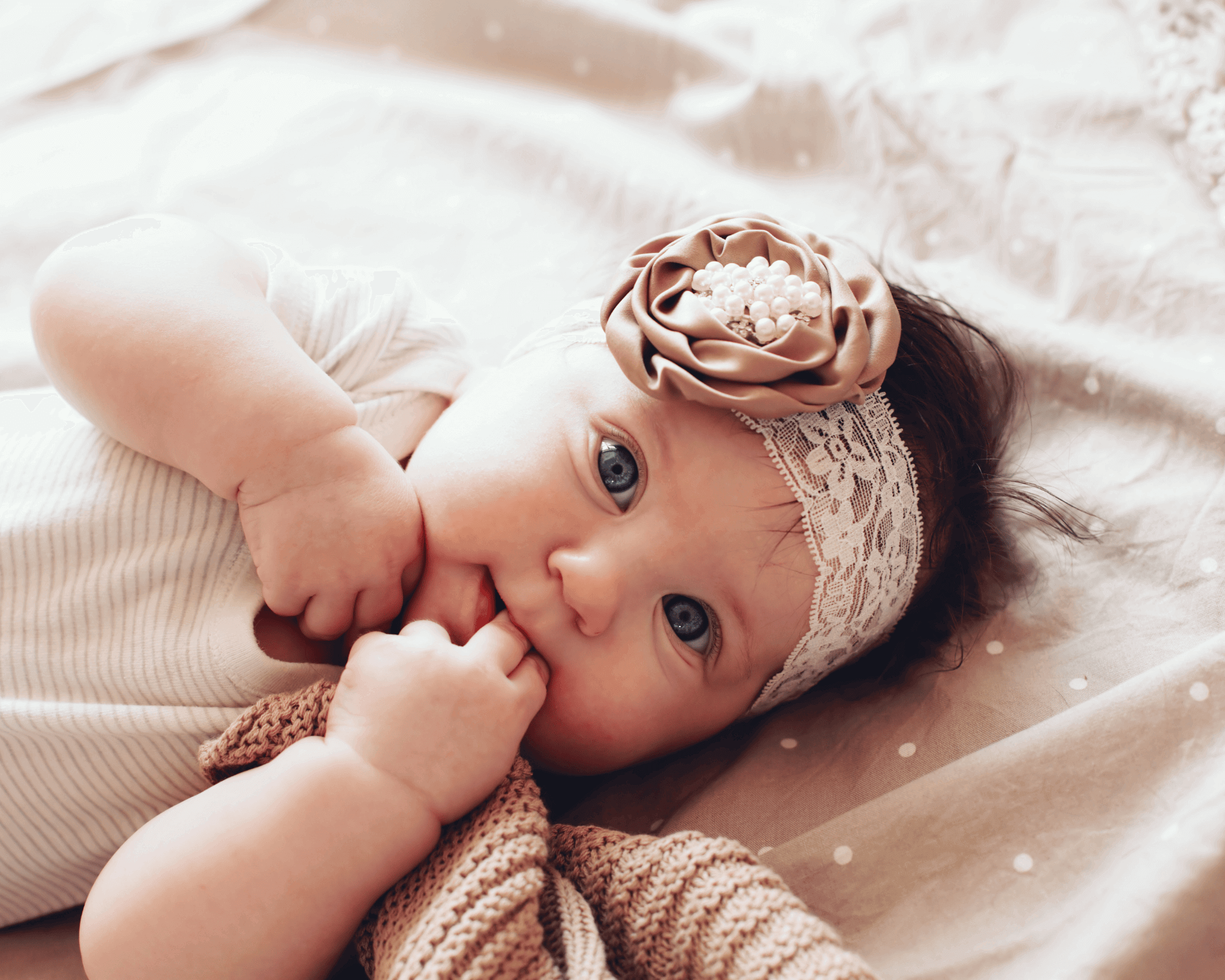 Baby girl with headband and lying on bed.