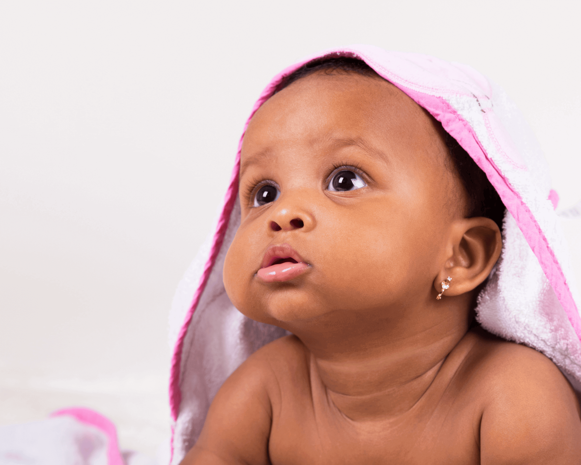 Baby underneath a pink blanket. 