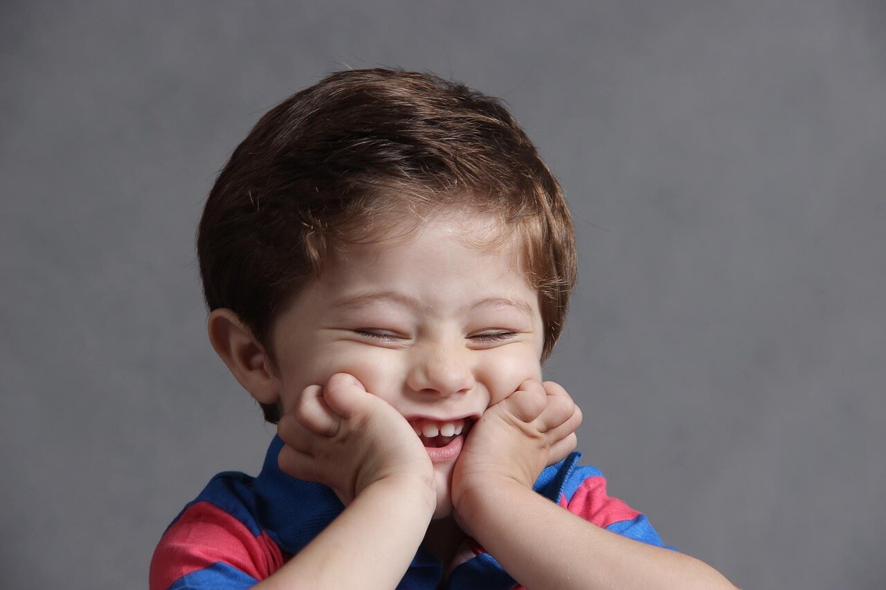 Boy with head in hands and smiling. 