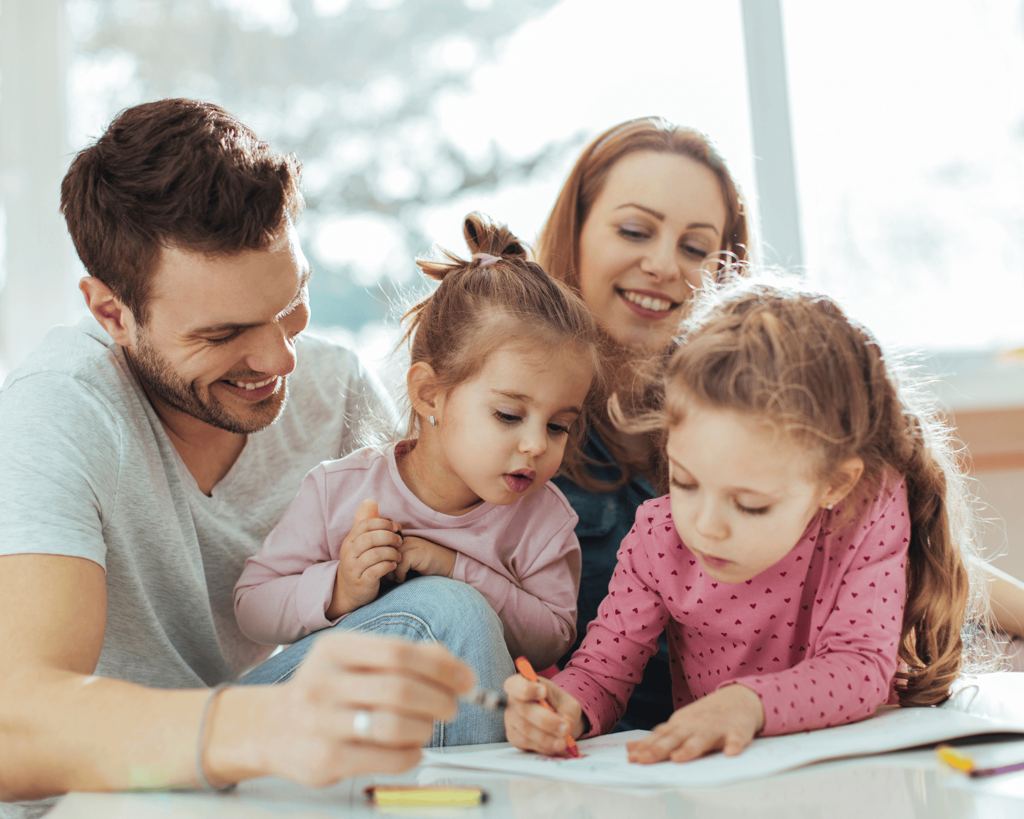 Mom and dad are watching their children colour. 