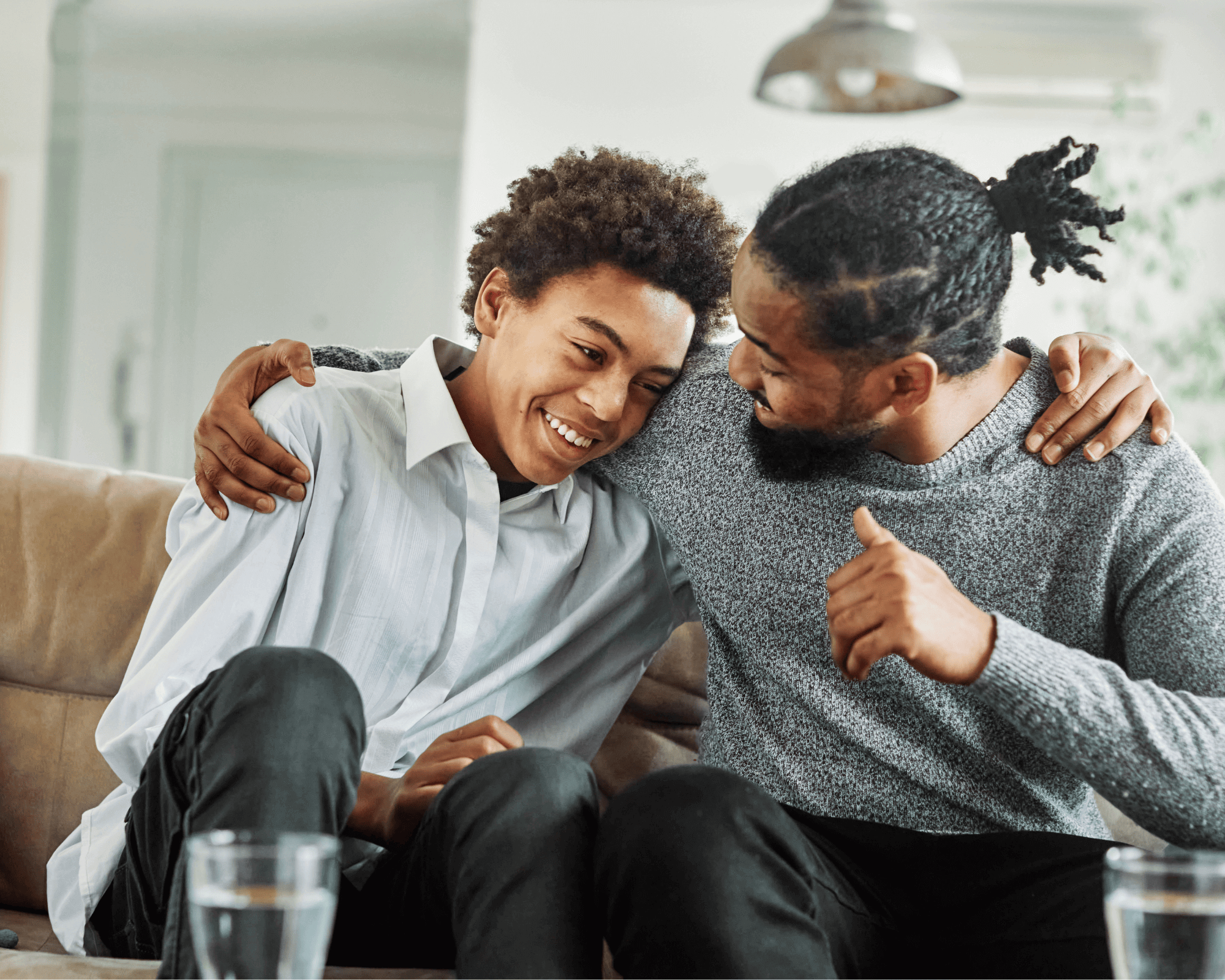 Father and older son on couch and hugging. 