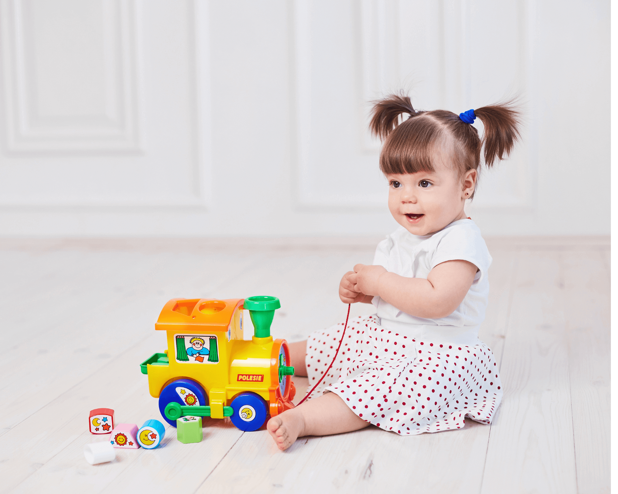 One year old girl playing with train.