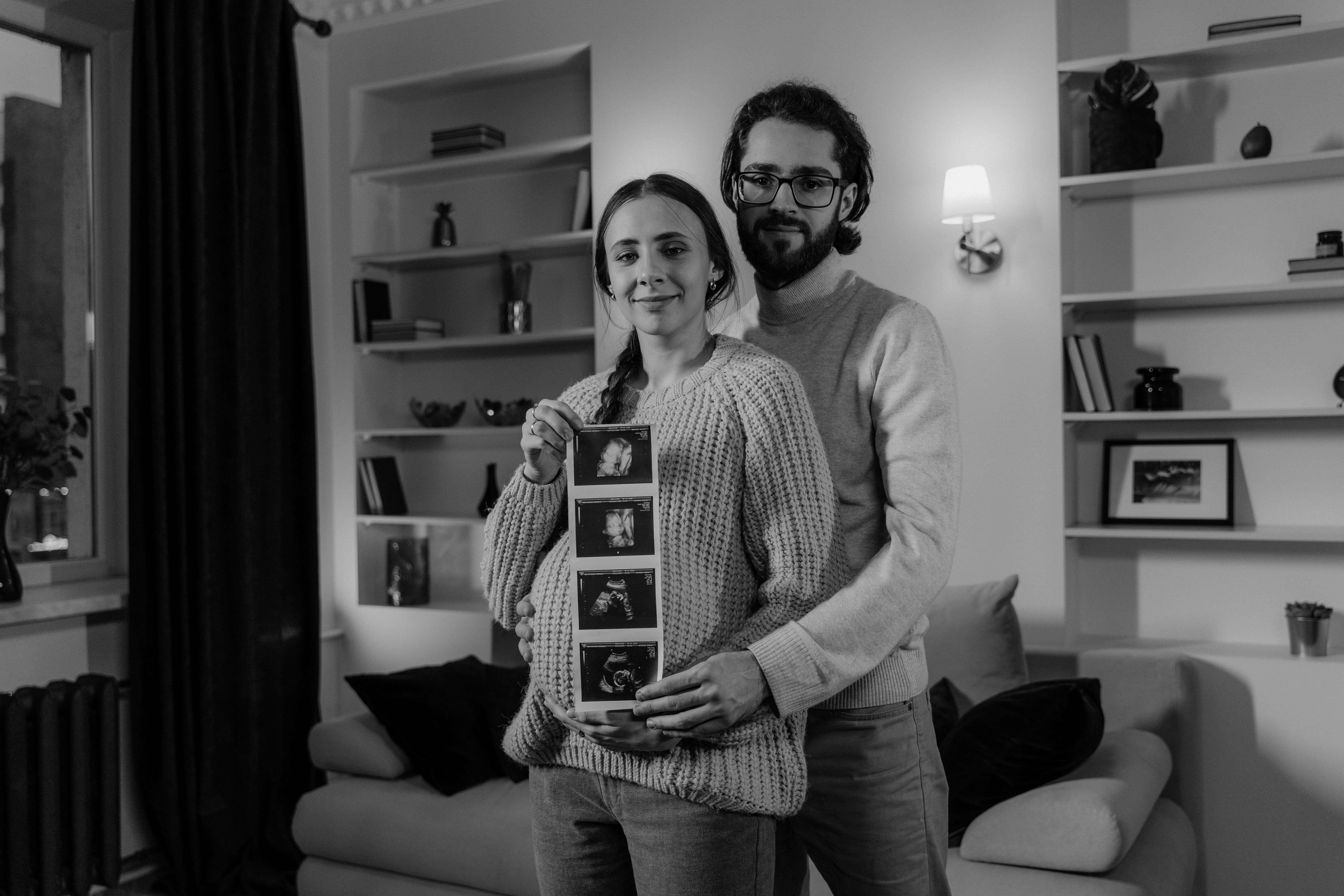 Pregnant Mom and dad are Holding up ultrasound pictures