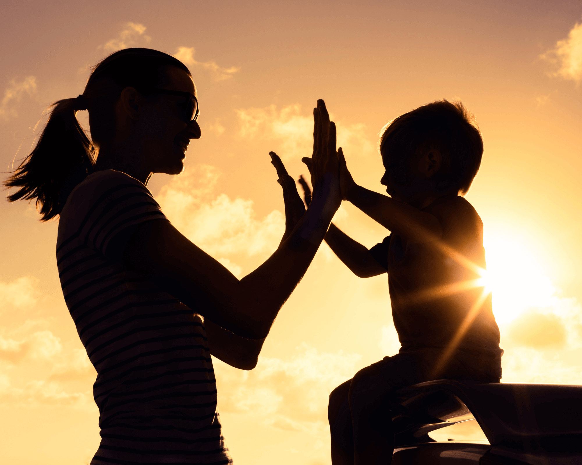 Mom and child playing clapping game at sunset. 