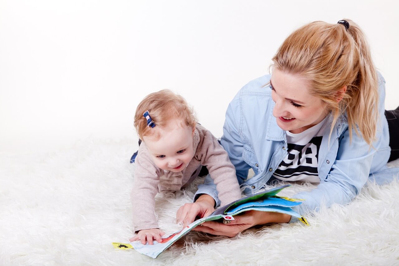 Mom reading book to her baby on the floor