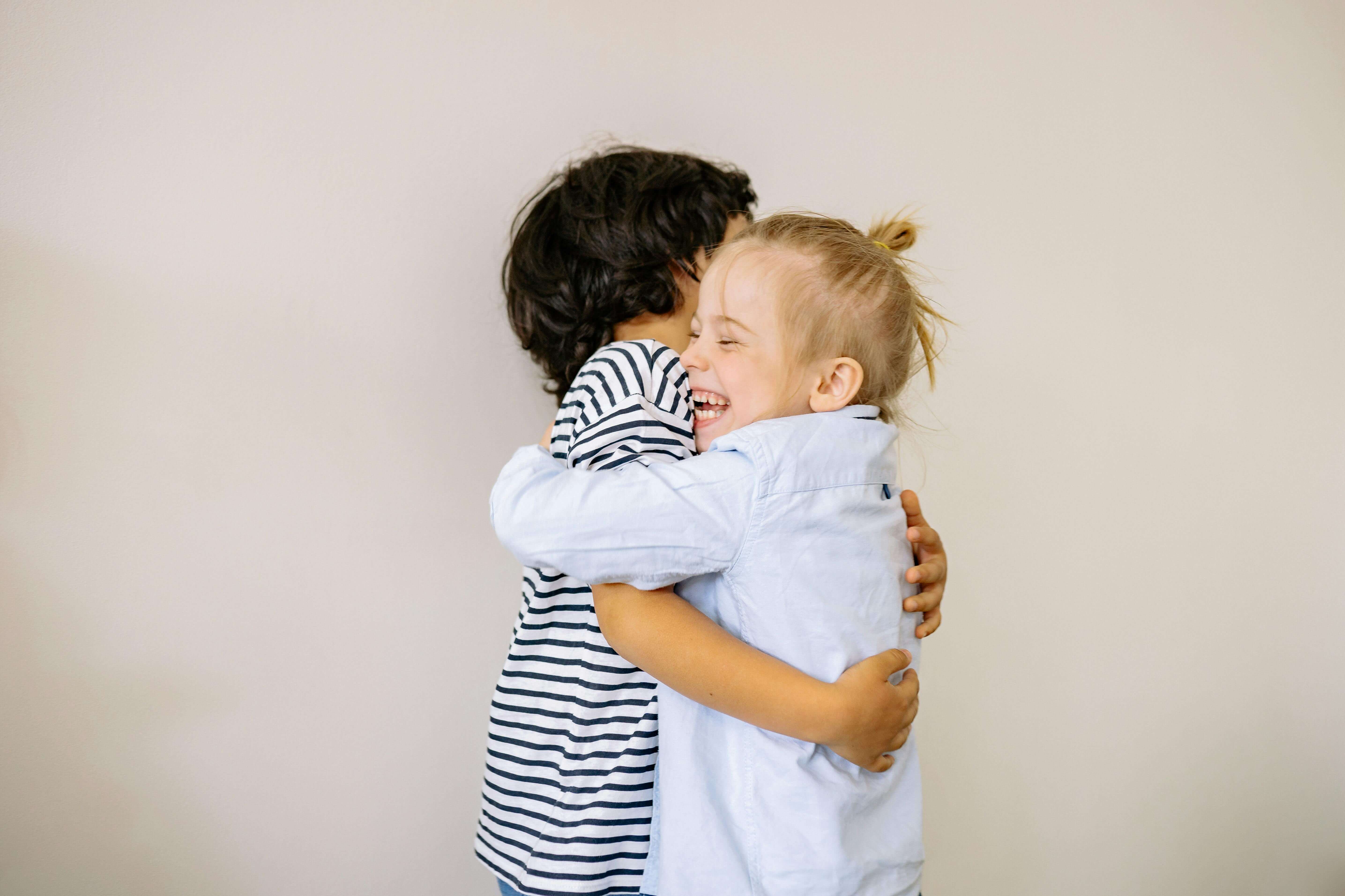 Two preschoolers hugging.