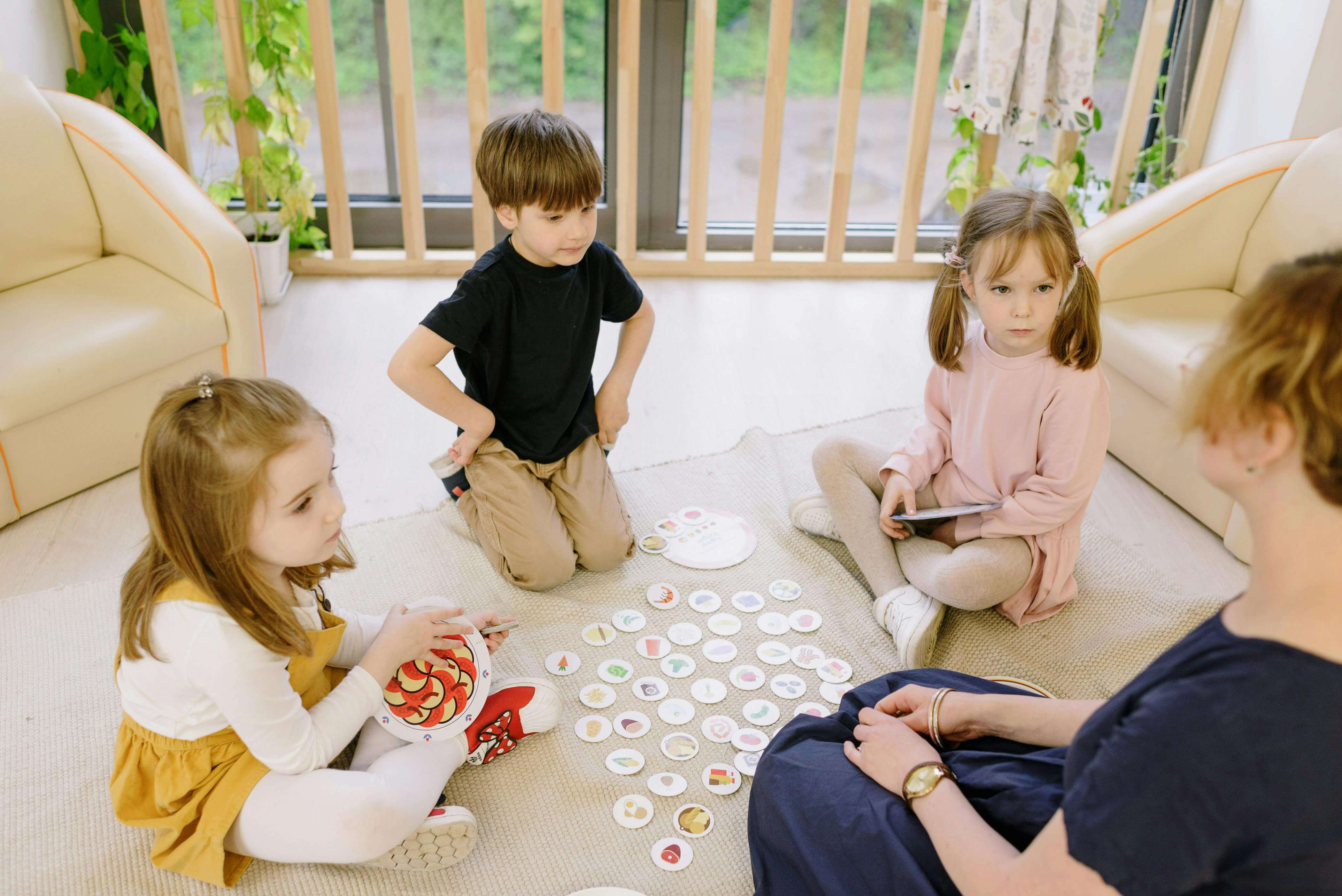 Three preschoolers sitting on floor and listening to teacher. 