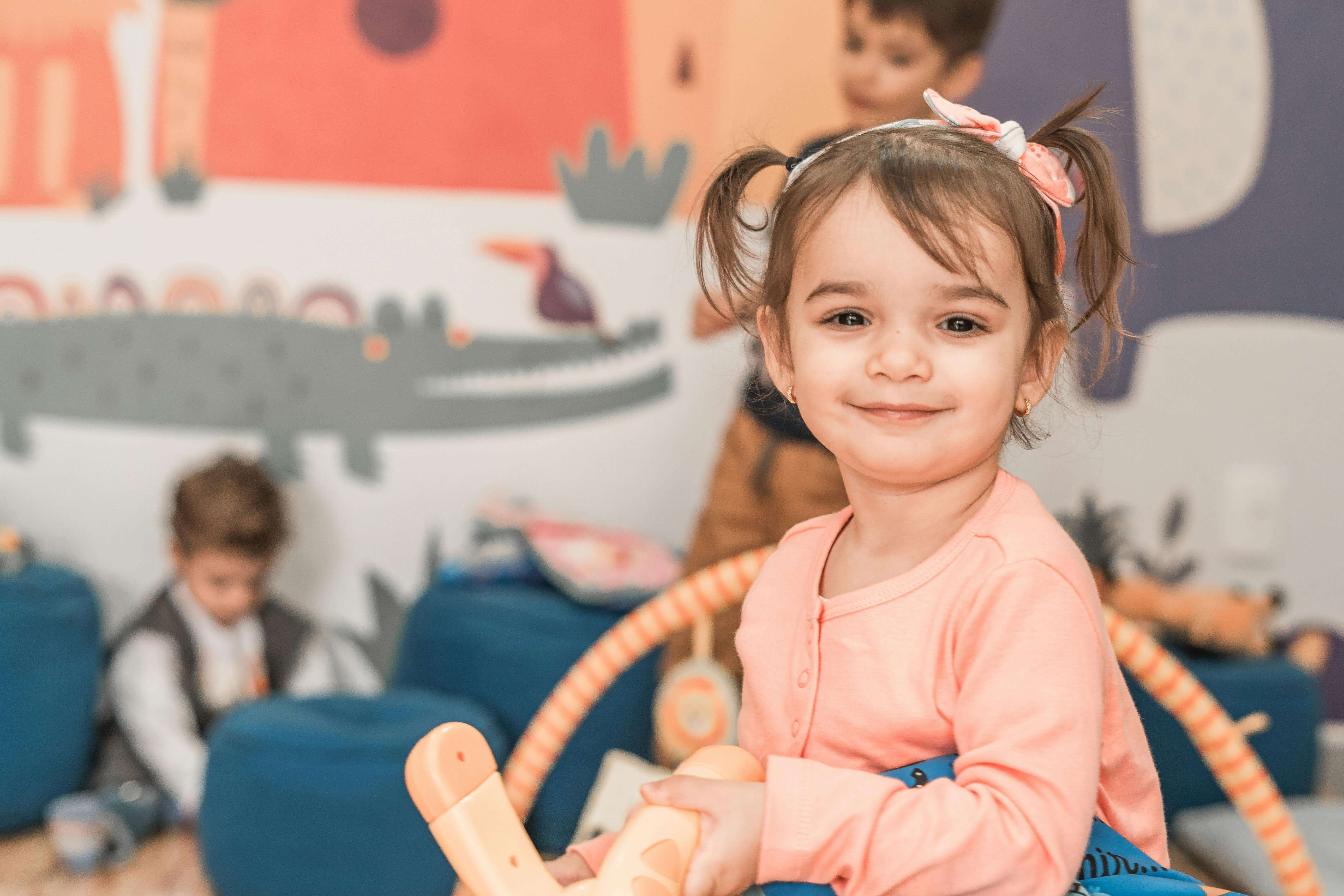 Preschooler looking towards camera holding toy and smiling. 