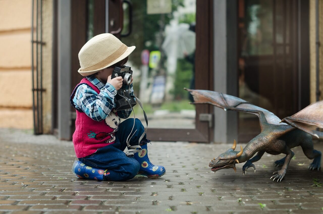 Toddler taking a photo opf an dinosaur.