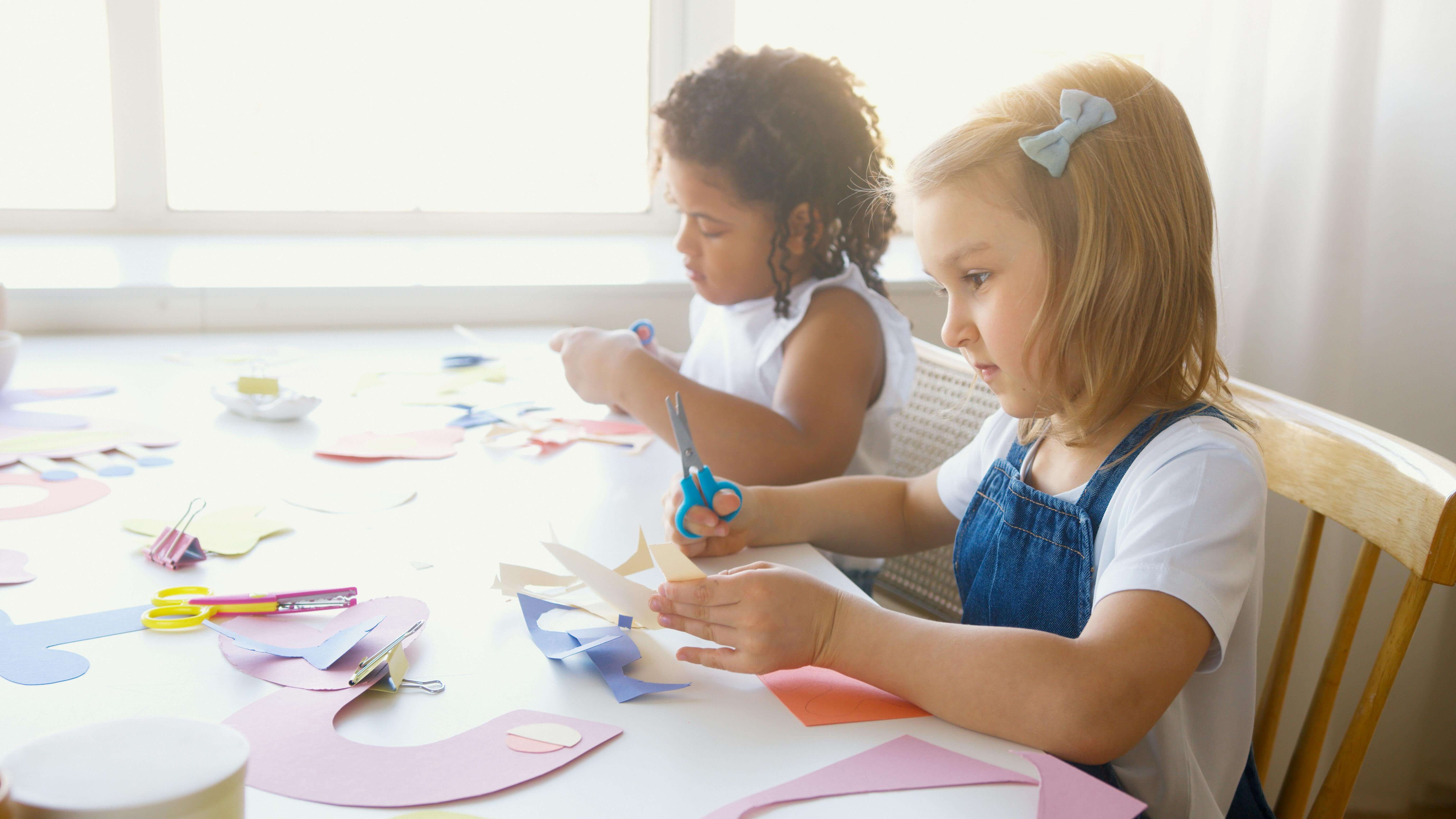 Two preschollers doing crafts at the table. 