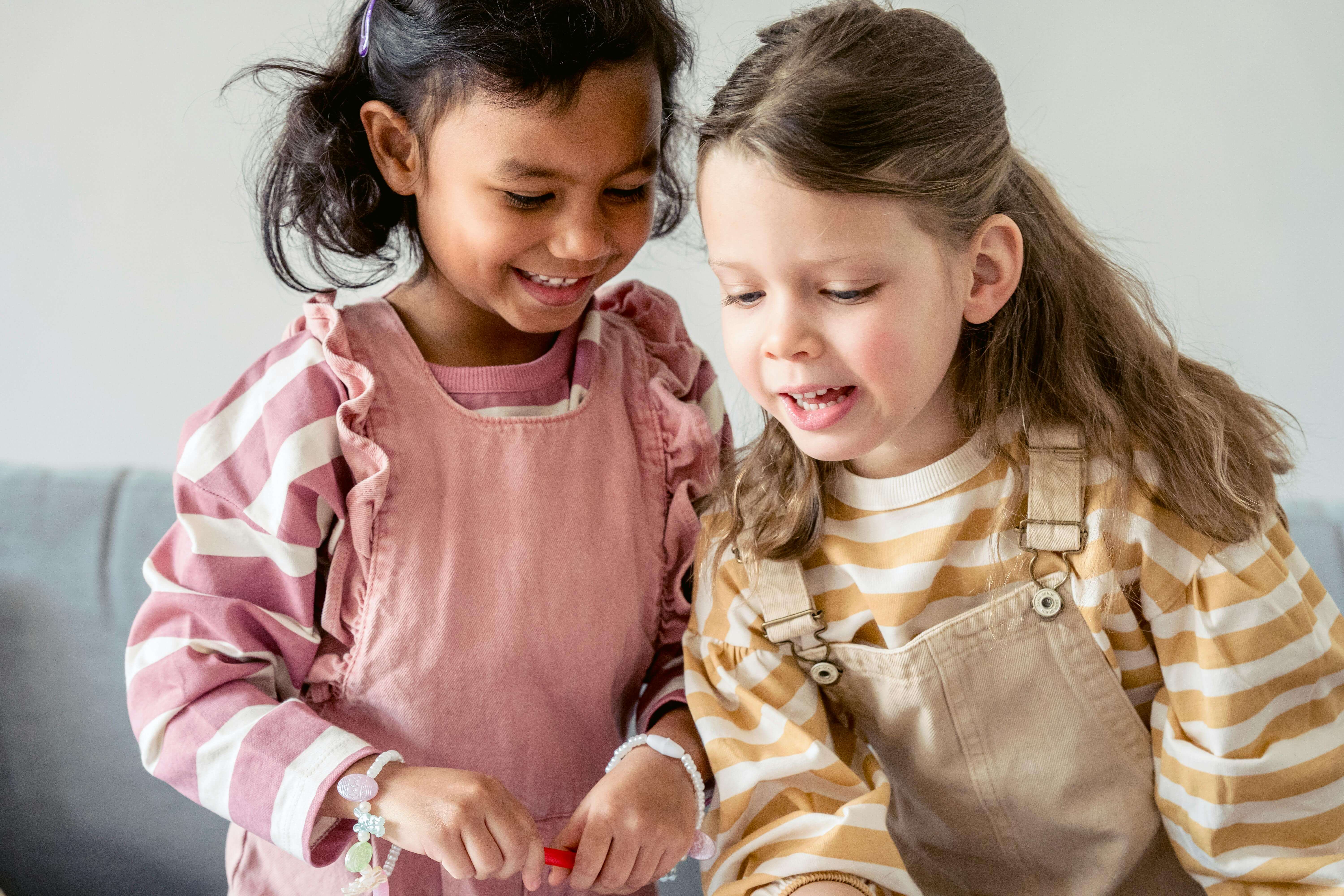 Two preschoolers lookingdown at something.