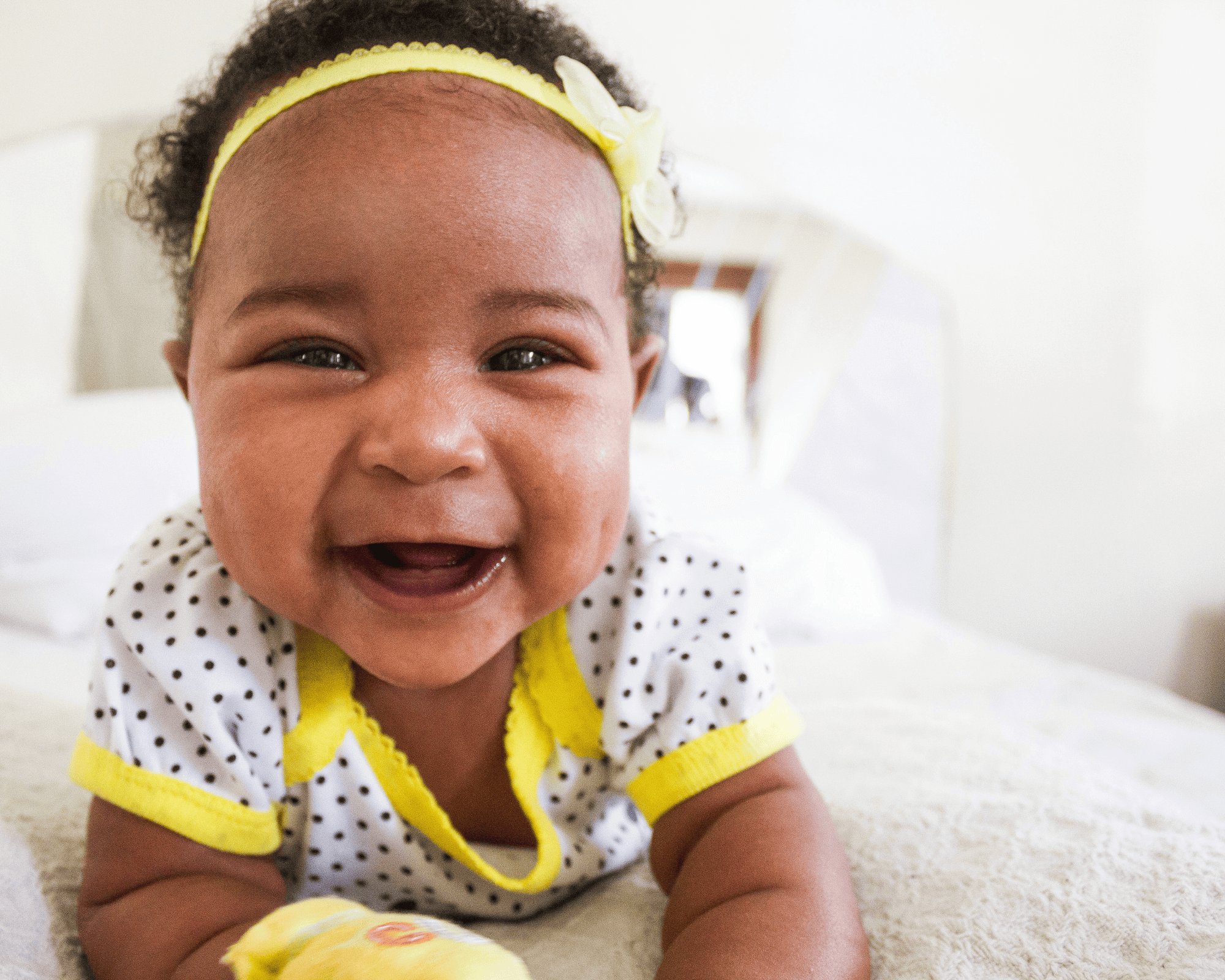 Baby girl lying on a blankey smiling with laughter in her eyes. 