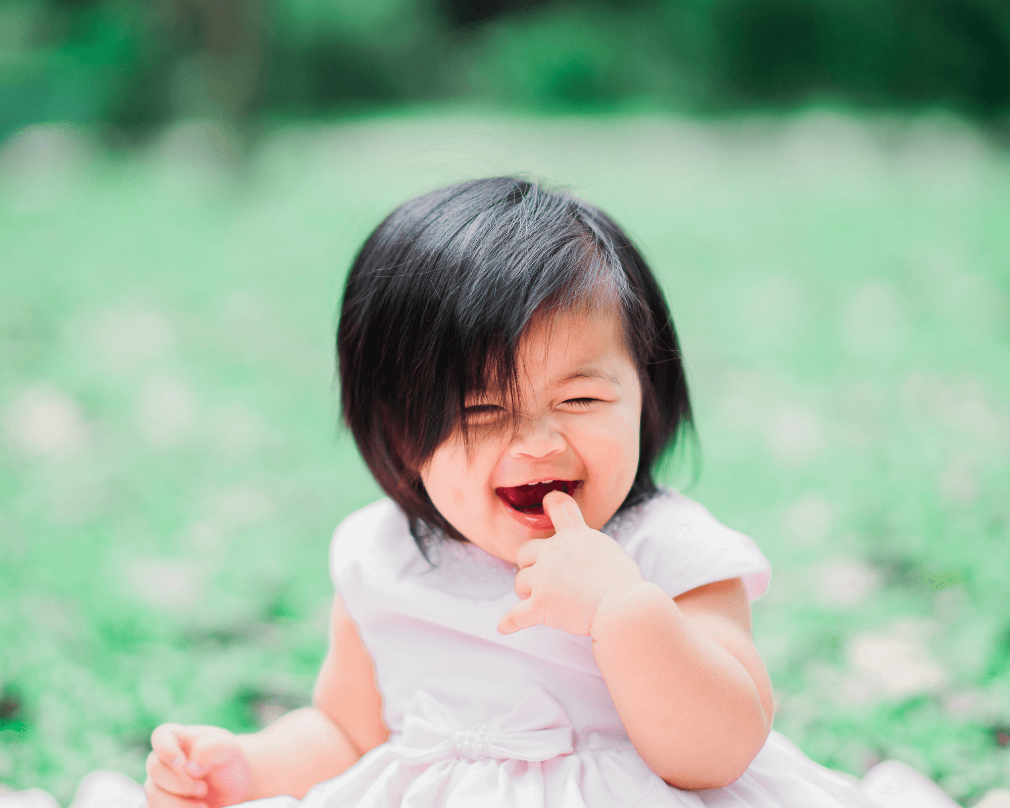 Baby girl sitting in nature on the ground.