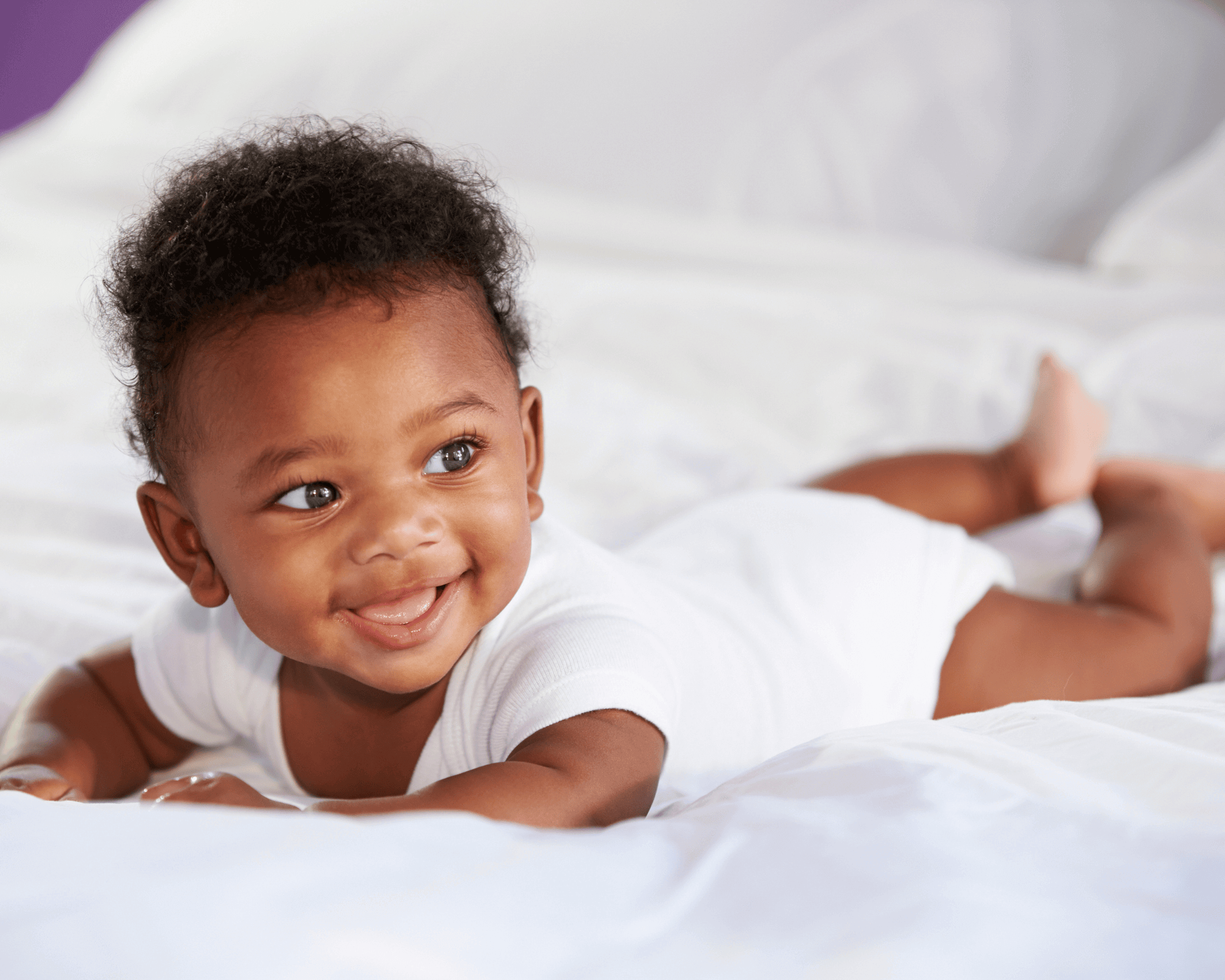 Baby boy lying on a white blankey.