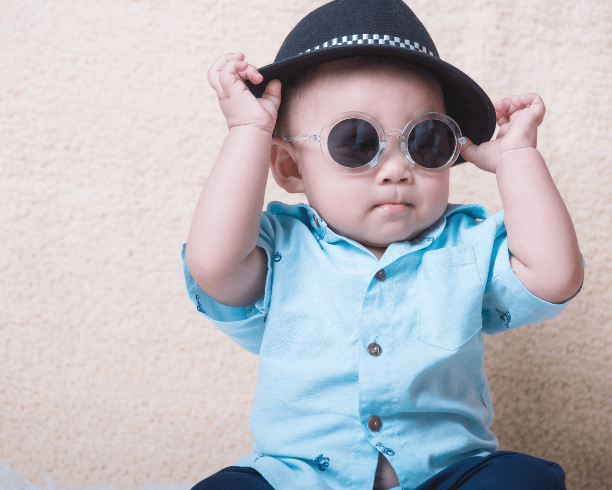 Baby boy wearing blue hat and sunglasses.