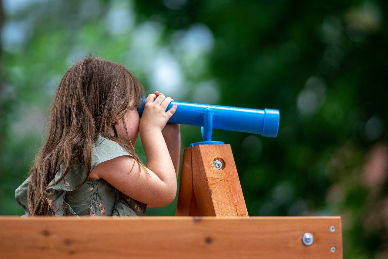 girl looking through toy telescope