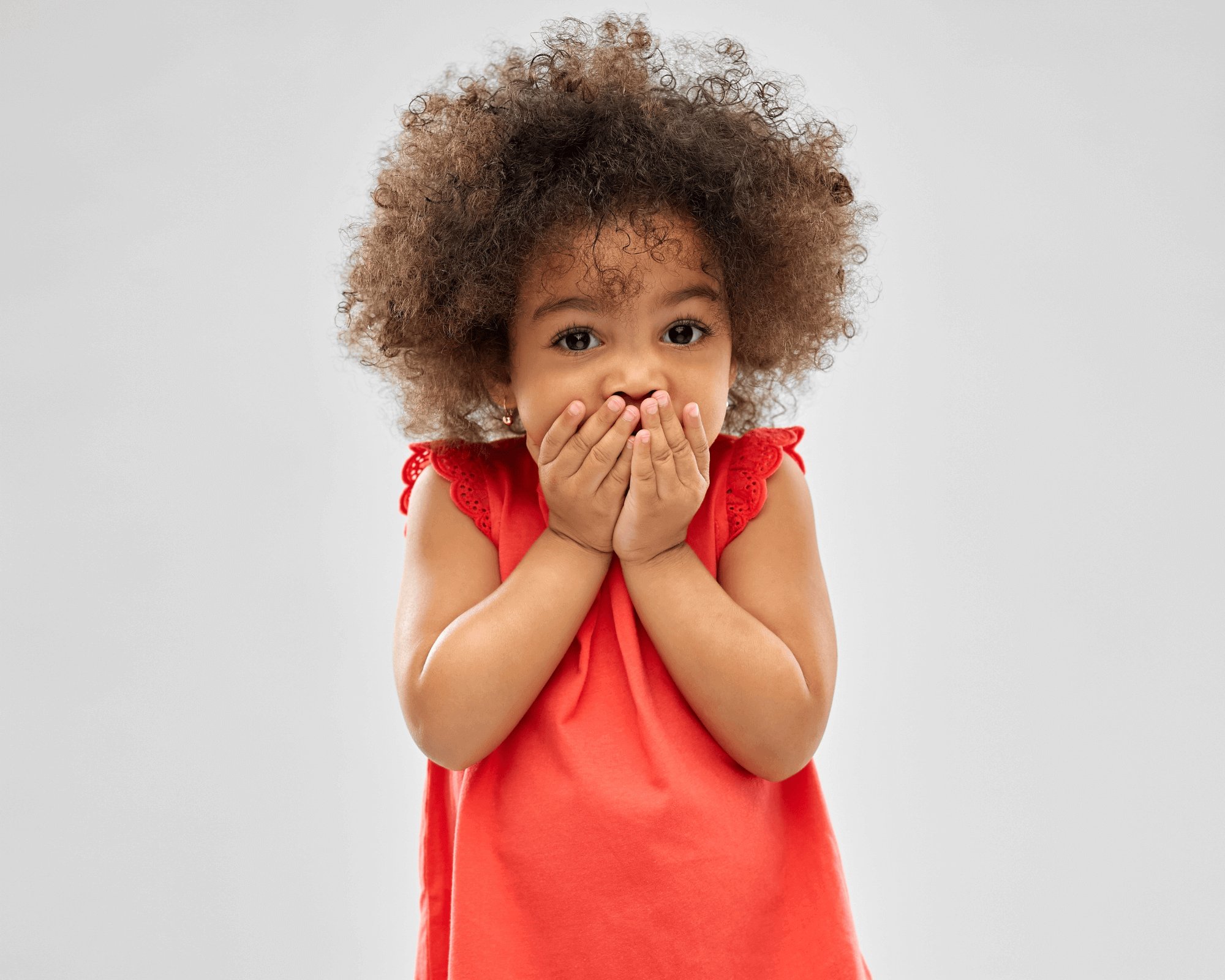 Little girl with her hands over her mouth. 