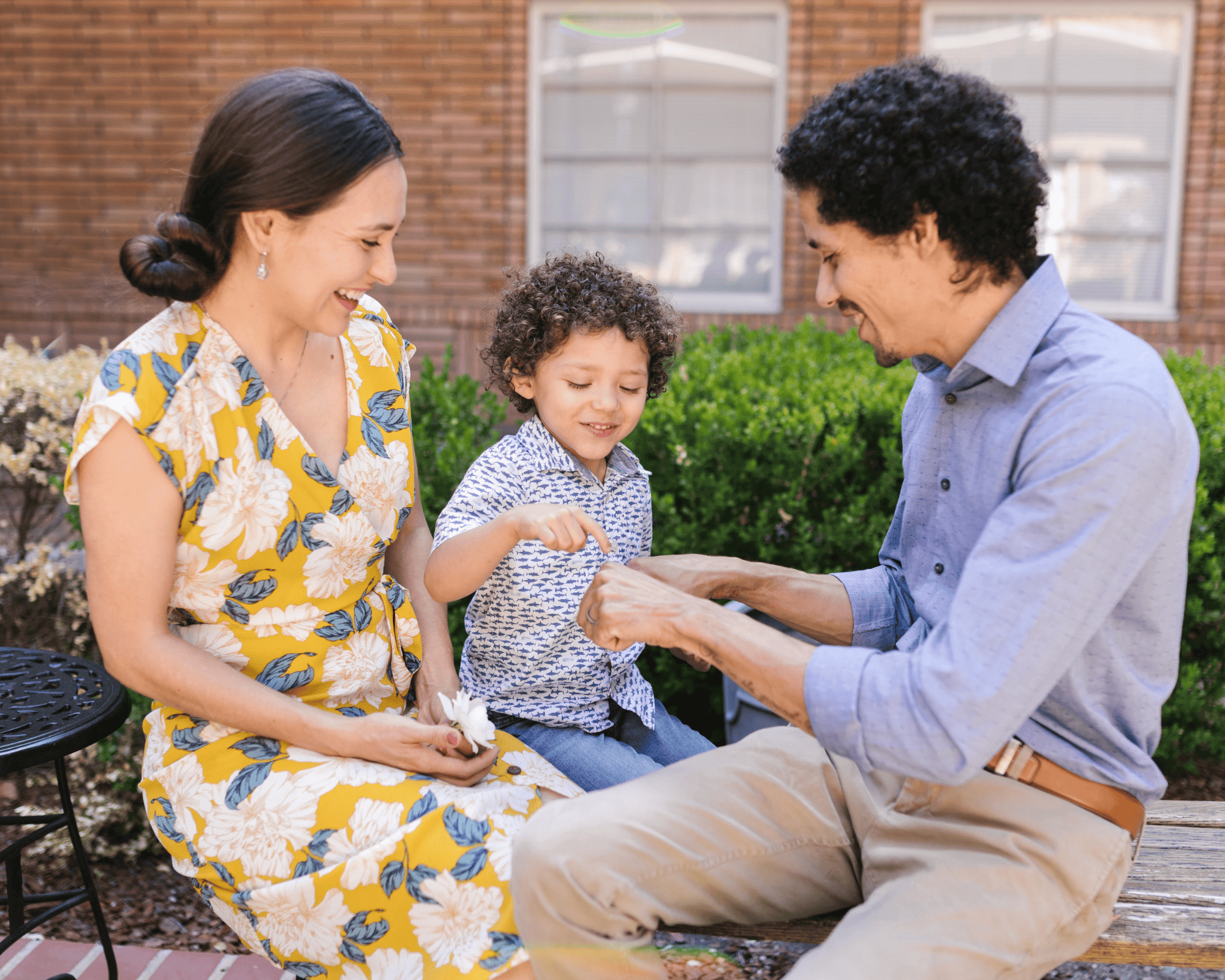 Parents and boy, dad is playing a fist game with boy.